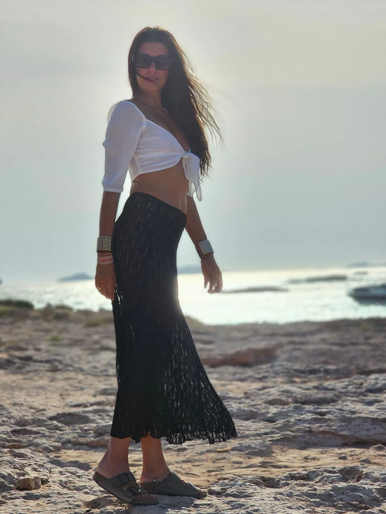 Lau junto al mar con blusa blanca y falda negra al atardecer