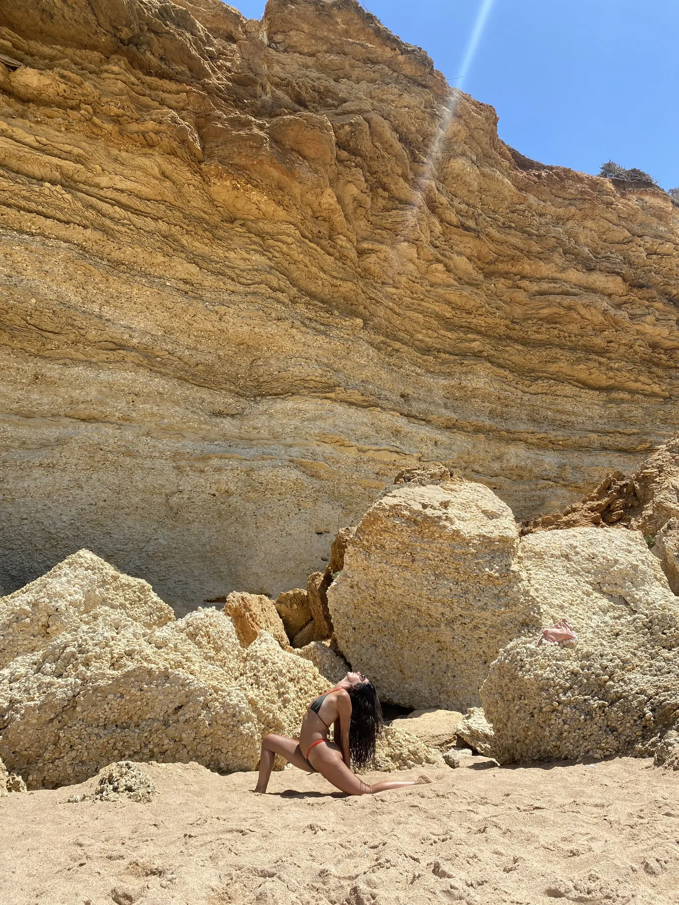 Laura en una postura de yoga en una playa, bajo un acantilado